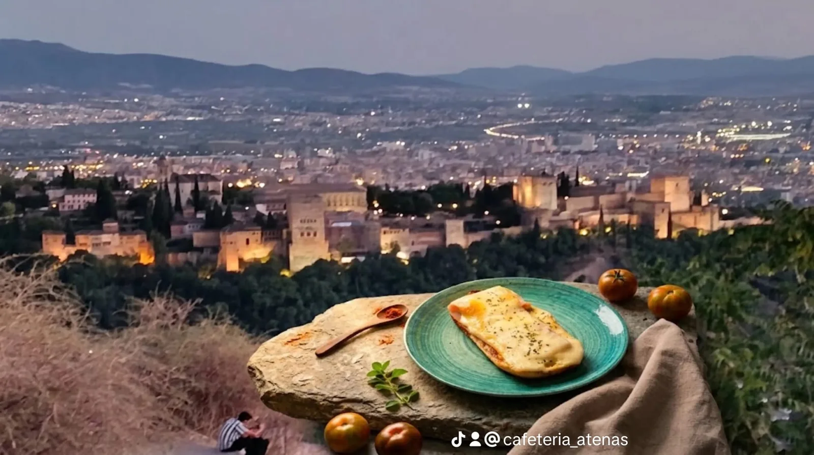 Tostada gratinada en plato turquesa con la Alhambra iluminada al fondo
